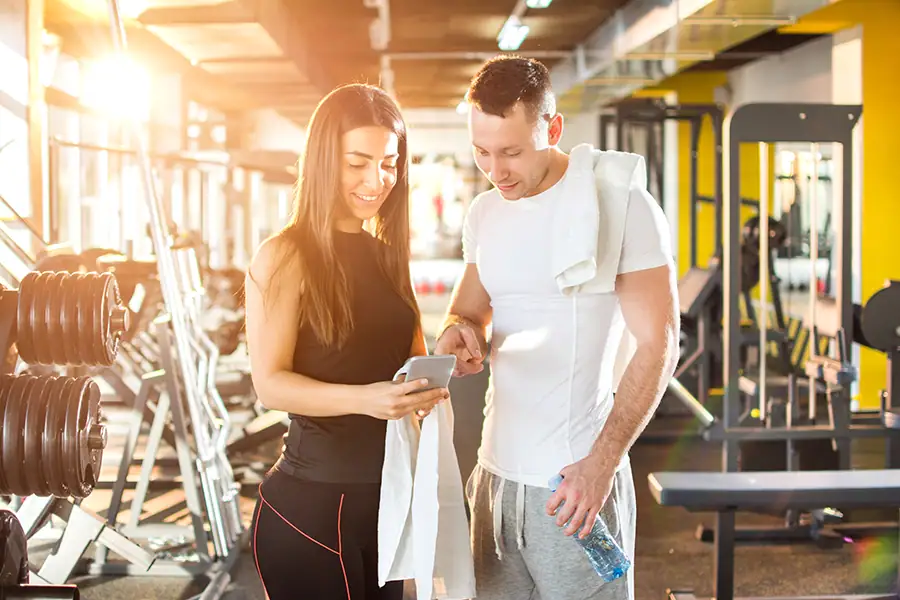 Personal trainer usando aplicativo de treino com aluno