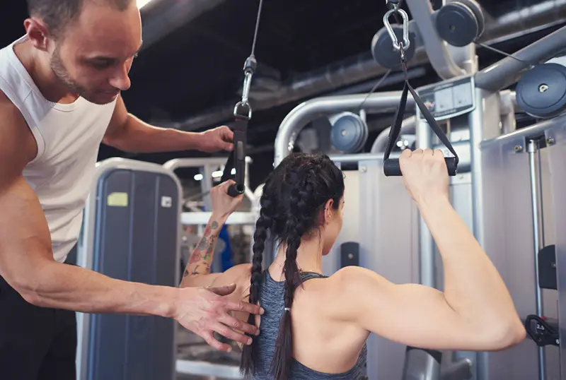 Personal Trainer avaliando a biomecânica de peitoral e dorsal em sua aluna