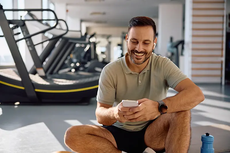 Homem na academia usando app de treino gratuito