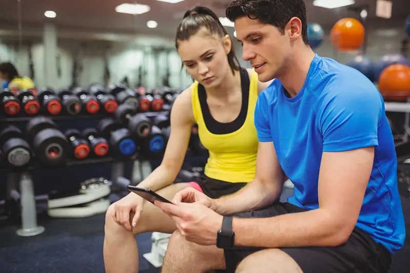 Personal trainer apresentando resultados em um tablet para justificar o valor da sua hora-aula